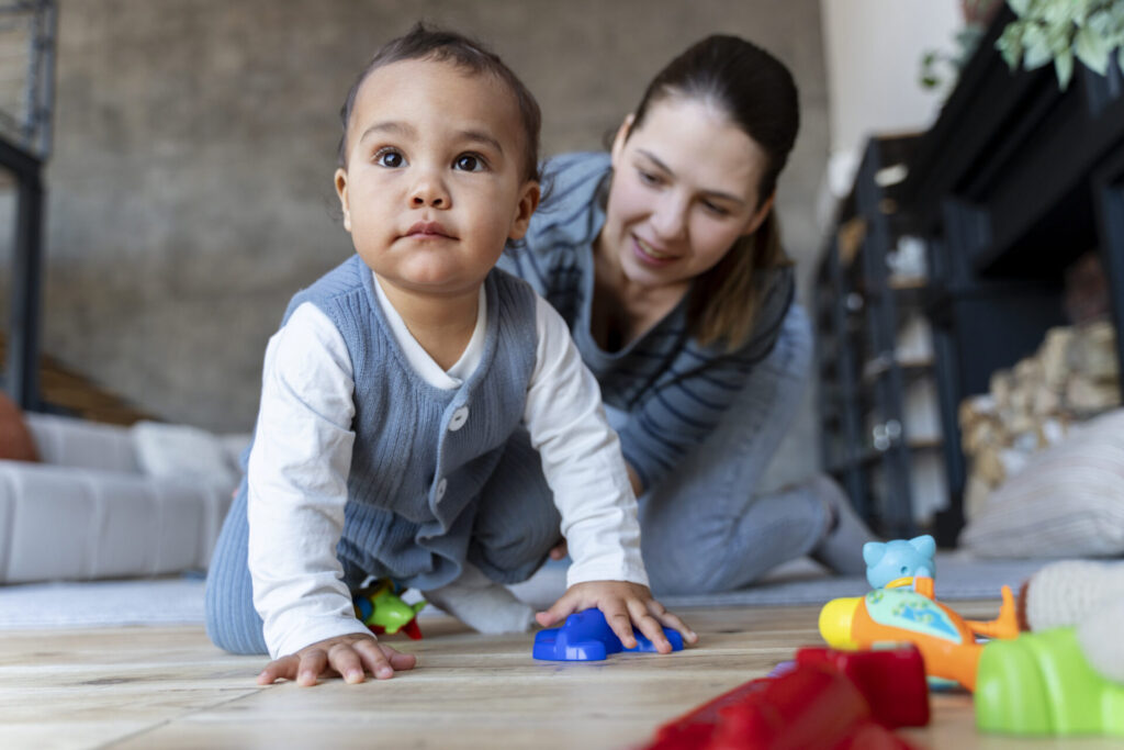 adorable baby crawling floor being helped by his mother